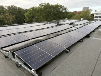 Zonnepanelen op een plat dak die zijn losgemaakt en gekanteld tegen elkaar aan staan tijdens de voorbereiding van dakrenovatie
